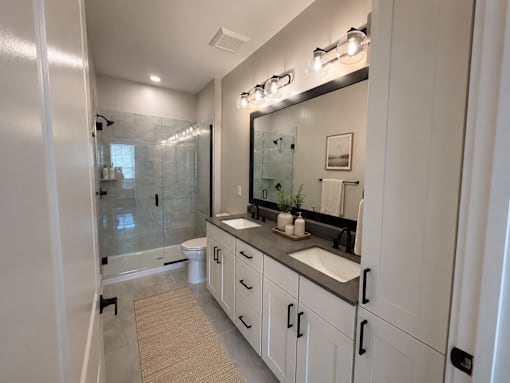 A bathroom with a sink, mirror, and shower.