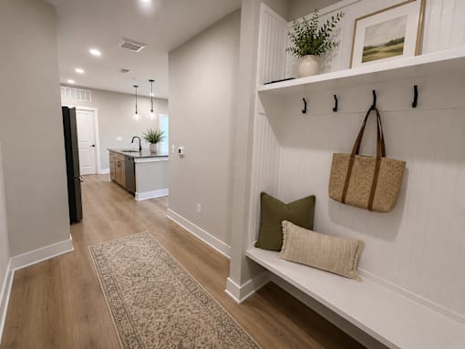 A hallway with a bench and a rug on the floor.