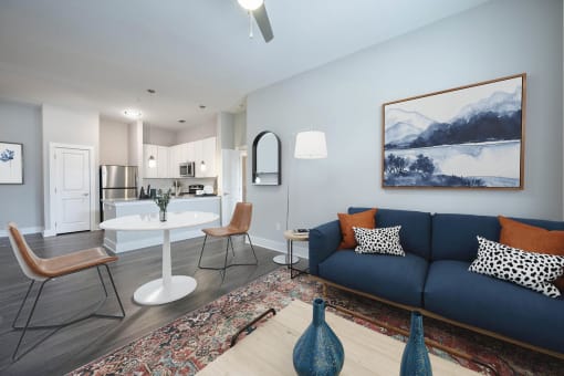 a living room with a blue couch and a white table and chairs