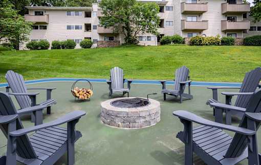 A fire pit surrounded by chairs in a courtyard.