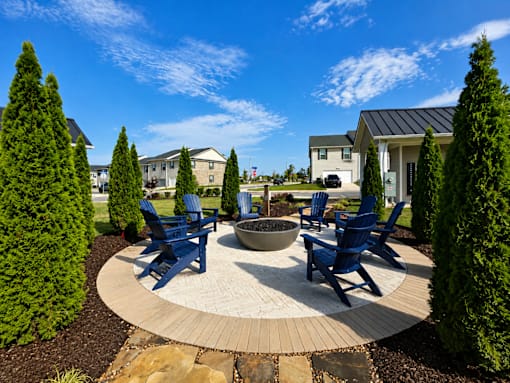 A circular patio with blue chairs and a fire pit in the middle.