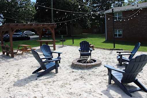 A sandy area with chairs and a fire pit.