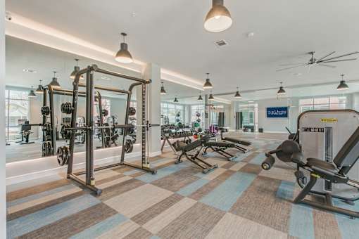 A gym with a variety of equipment including treadmills, weights, and exercise machines.