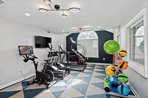A room with a treadmill, exercise bike, and a television.