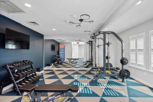 A gym with a variety of equipment including weights and benches.