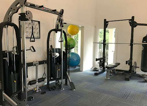 A gym with a variety of equipment including a weight bench, a leg press machine, and a squat rack.