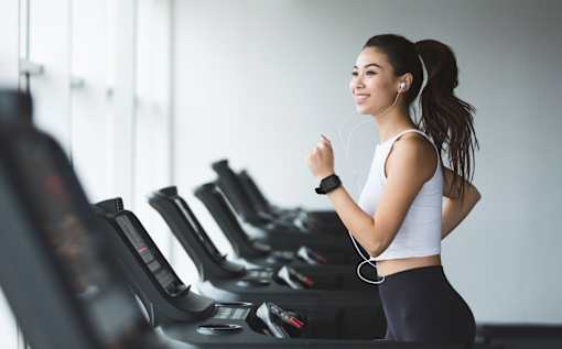 A woman is running on a treadmill in a gym.