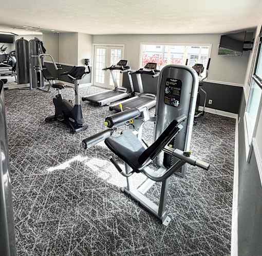 A gym with a variety of equipment including treadmills, weights, and exercise machines.