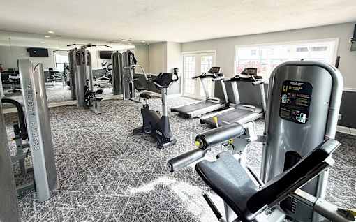 A gym with a variety of equipment including treadmills, weights, and exercise machines.