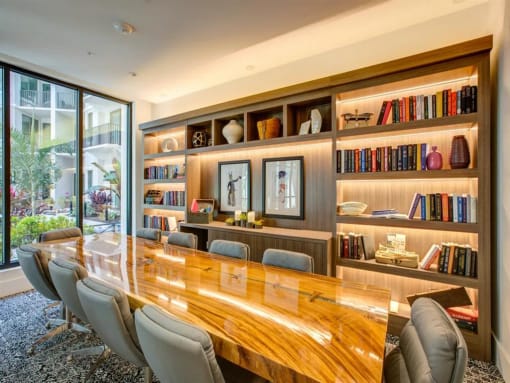 a large wooden table sits in front of a large bookshelf at Altis Grand Central, Florida, 33606