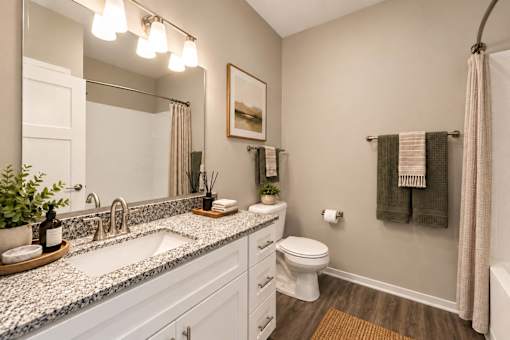 A bathroom with a white toilet, sink, and a mirror.