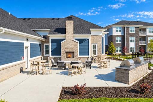A patio with a fireplace and chairs is surrounded by a brick wall.