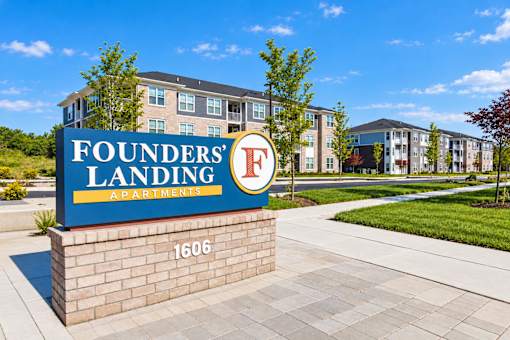 A sign for Founders Landing Apartments in front of a building.
