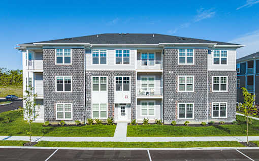 A large apartment building with a parking lot in front.