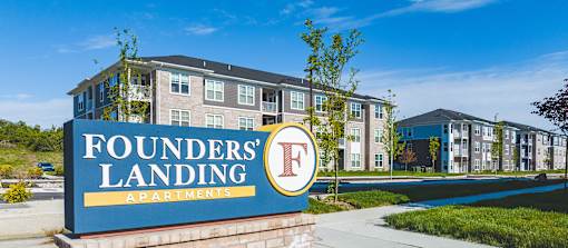 A sign for Founders' Landing Apartments in front of a building.