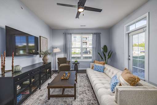 A living room with a large couch, a coffee table, and a flat-screen TV.
