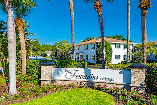 The entrance to The Fountains of Largo, a gated community with white houses and palm trees.
