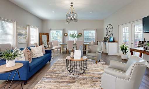 A living room with a blue sofa and white chairs.
