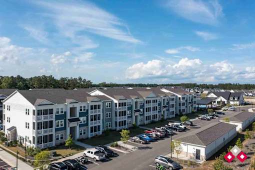 A large apartment complex with multiple buildings and a parking lot in front.