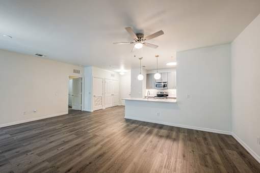 A spacious room with a ceiling fan and wooden flooring.