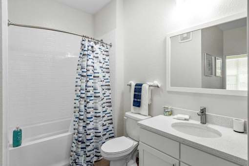 A white bathroom with a toilet, sink, and shower curtain.