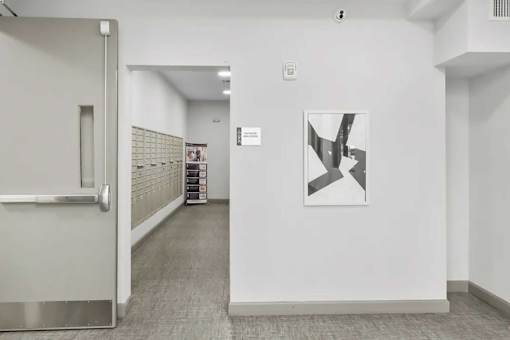 A hallway with a white door and a painting on the wall.