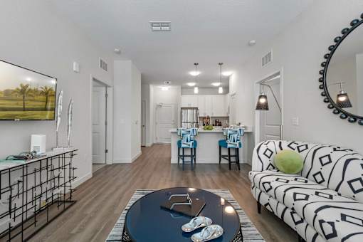A living room with a black and white patterned couch and a coffee table with a pair of baby shoes on it.