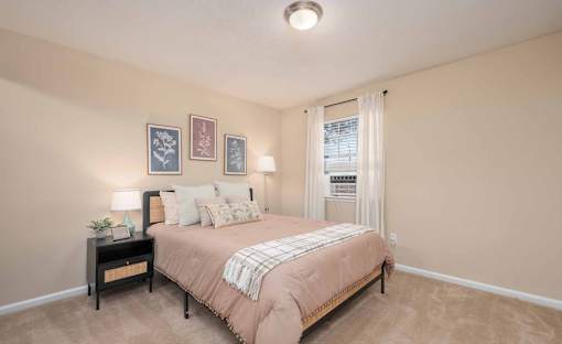 A bedroom with a bed, nightstand, and pictures on the wall.