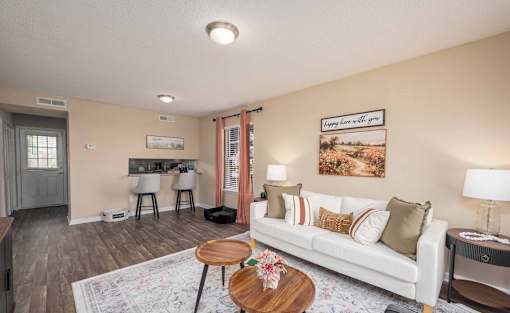 A living room with a white couch, a coffee table, and a painting on the wall.