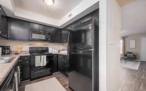 A black fridge in a kitchen with black cabinets.