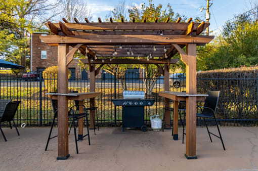 a pergola with two tables and a grill