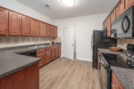 A kitchen with wooden cabinets and a black refrigerator.