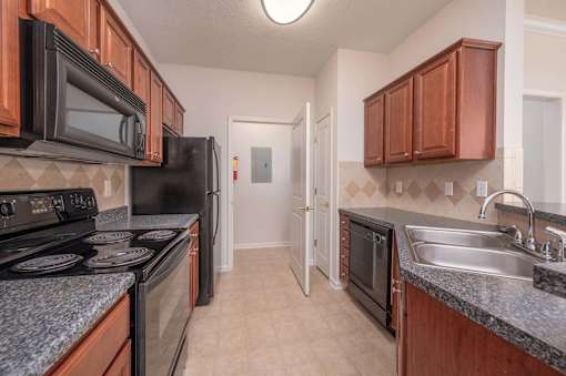 A kitchen with black appliances and brown cabinets.
