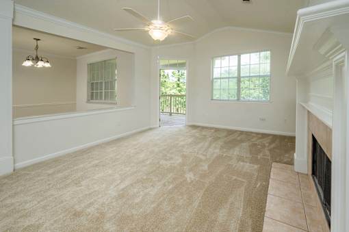 A spacious living room with a fireplace and a ceiling fan.
