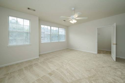 A room with a carpeted floor and a ceiling fan.