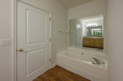 A white bathroom with a tub and a mirror.