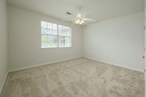 A room with a ceiling fan and a large window.