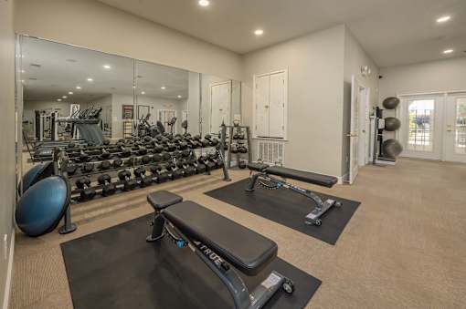 A gym with a mirror, weights, and exercise equipment.