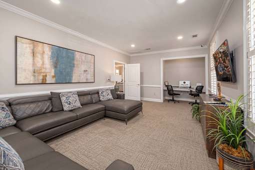 A living room with a grey couch and a painting on the wall.