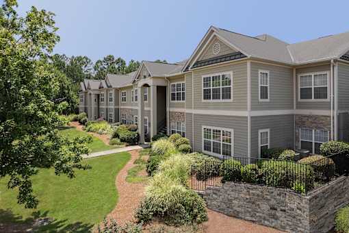A large grey house with a stone wall in front.