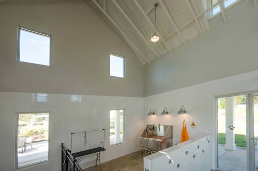A room with a white ceiling and walls, a window, a table, and a bench.
