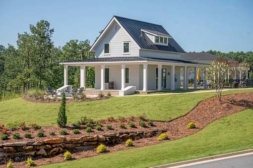 A white house with a black roof and a porch.