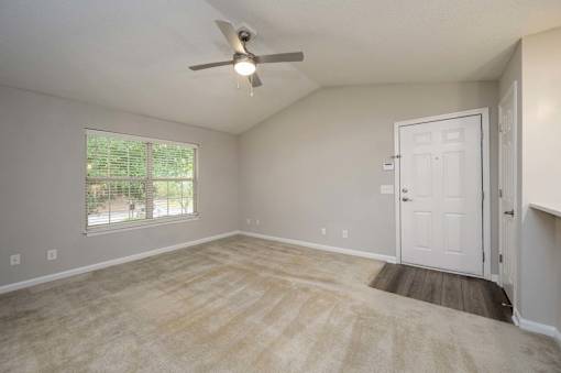 A room with a ceiling fan and a door leading to another room.