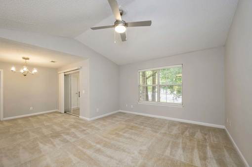 A room with a ceiling fan and a window with blinds.