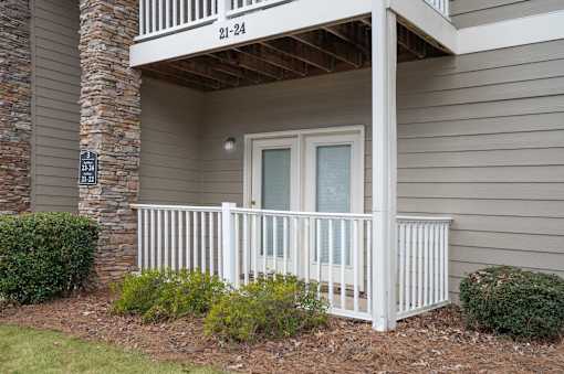 A balcony with a white railing and a glass door is on the second floor of a house.