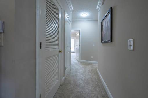 A hallway with a light on the wall and a painting hanging above it.