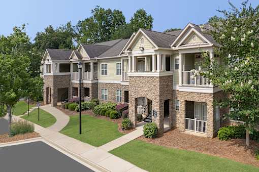 A large, two-story house with a stone facade and a balcony on the second floor.