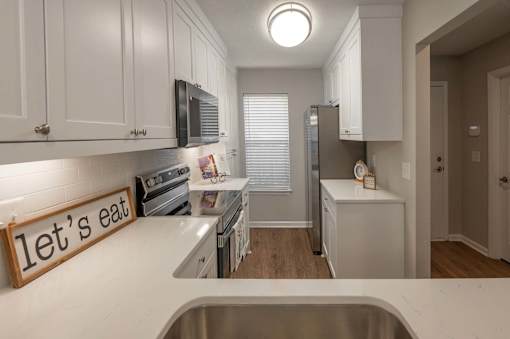 A kitchen with a sign that says "let's eat" on the counter.