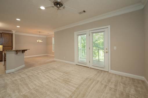 A room with a carpeted floor and a ceiling fan.