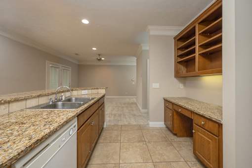 A kitchen with granite countertops and wooden cabinets.